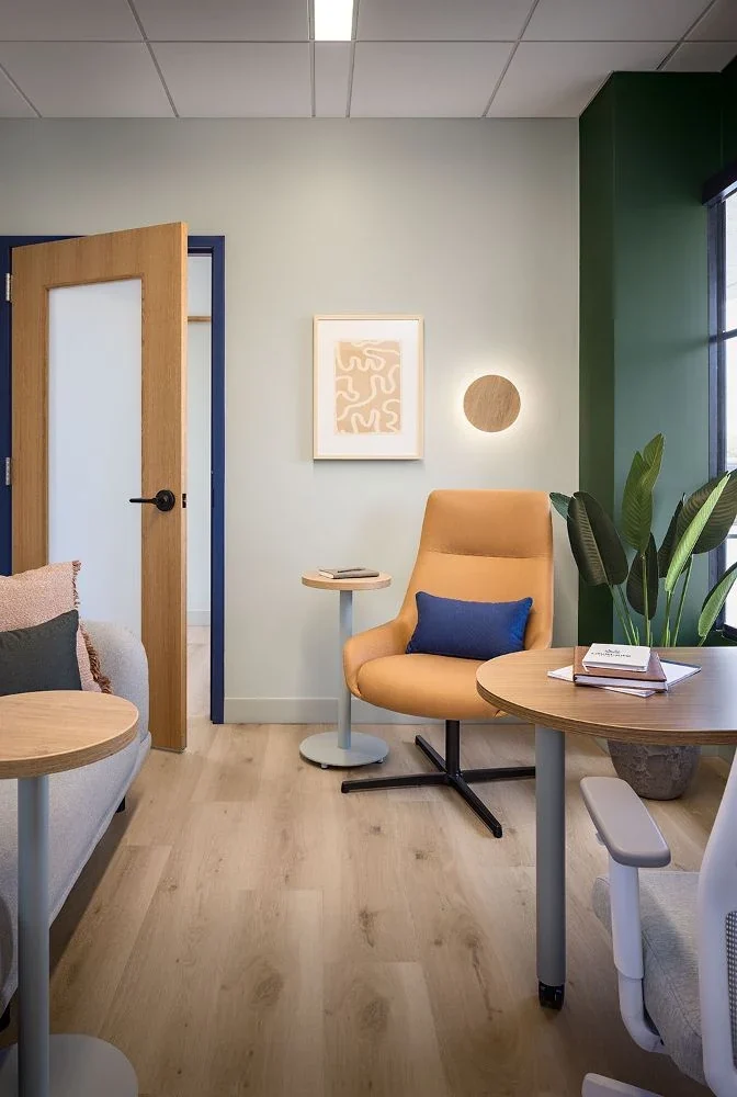 Therapy room with a tan swivel chair, a glowing round wall light, and a deep green accent wall